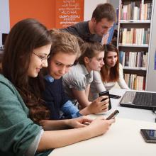 Teenagers using tablet and desktop computers in the library. Photo by Adam Mikosz.