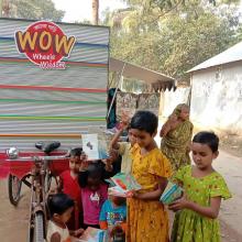 Children collect books from the three-wheeled library, parked in a street in a poor area of Dhaka.